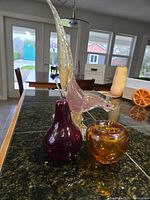 Murano pheasant with purple pear and amber apple on countertop