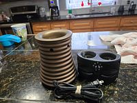 Brown ceramic warmer and black double-well warmer on countertop with cord visible