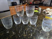 Seven clear glass tumblers arranged on countertop