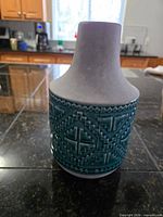 Full view of vase front showing grey neck, teal patterned midsection, grey base
