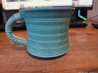 side view of teal handmade mug highlighting glaze and horizontal rings
