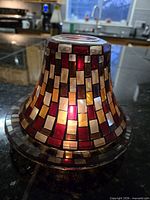 Shade on plate with tealight lit to show mosaic glass coloration