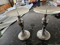 Two stainless steel candle holders standing upright