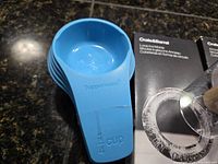Stacked blue Tupperware measuring cups beside ice mold box