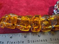 Close-up of amber-tone stretch bracelet showing panel detail and ruler for scale