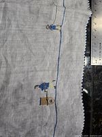 Close-up of figure with spinning wheel along blue border and scalloped edge detail