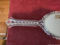Front view of clear Lucite hand mirror showing handle and mirror glass