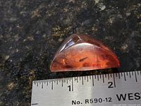 Front view of amber brooch beside ruler