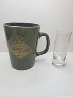 Mug and shot glass side by side displaying logos