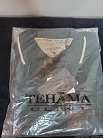 Front of sealed package showing folded green polo and Tehama branding