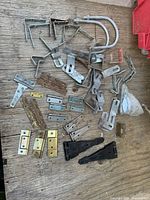 Overview of assorted hinges, brackets, U-bolts spread on wooden surface