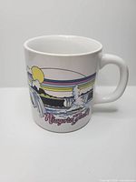 Front view of ceramic mug showing Niagara Falls illustration and rainbow design