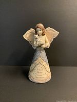 Front view of angel figurine holding cat with inscription visible