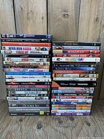 Two tall stacks of DVD cases on wooden backdrop showing variety of titles