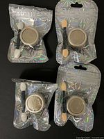 Four sealed holographic pouches showing jars and applicators