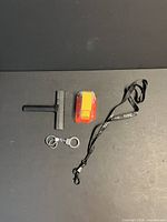 All four items laid out: Leon's diecast truck in package, handcuff keychain, black lanyard, black scraper