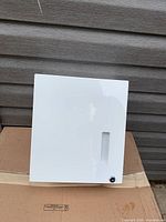 Front view of white metal cabinet showing viewing slot and cam lock