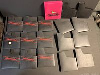Group shot of all sleeves laid out: 12 black with red Nintendo logo, 10 plain black, 1 pink Nintendo sleeve