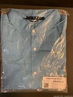 Shirt folded in sealed amazon essentials plastic bag showing buttons, collar, size label