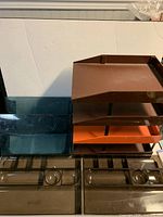 Group view of all trays: two smoke Eldon catch-alls, four brown/orange letter trays, two teal letter trays