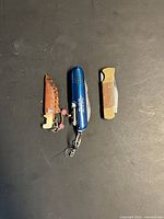 All three items closed: blue pocket knife, wood-inlay pocket knife, carved knife charm with sheath