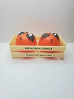 Front view of two orange shakers seated in labeled crate