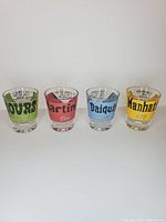 Front view of four colored cocktail recipe shot glasses