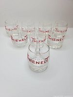 All eight Thienelt shot glasses arranged, showing logos and condition
