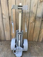 Front view of folded Spalding push cart showing wheels, frame, and straps