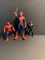 Three Spider-Man figures standing side by side showing relative sizes and colors