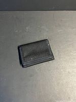 Closed black nylon trifold wallet on flat surface