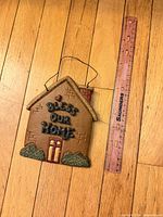 Front view of house-shaped plaque beside ruler for scale