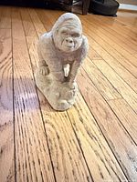 Front view of concrete gorilla figurine on hardwood floor