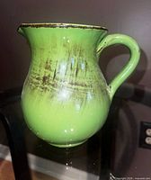 Profile view of green ceramic pitcher showing color and brush accents
