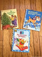 Three Little Golden Books laid out on wooden floor