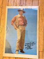 Full view of John Wayne color poster in plastic sleeve