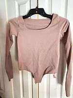 Front view of Skims long sleeve bodysuit hanging on hanger