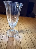 Full view of clear cut crystal pedestal vase standing on hardwood floor