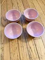 Top view of four matching pale pink bowls on wood floor