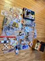 Overview of all jewelry-making supplies spread on floor: bags of beads, findings, cords, boxes