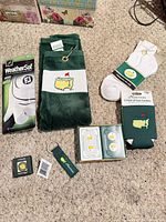 All items laid out on carpet: glove, towel, socks, can coolers, playing cards, keychain, pin