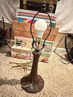 Full view of metal table lamp showing base, column, harp, socket with LED bulb and cord