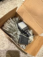 Box containing coiled clear-wire LED string lights and controller