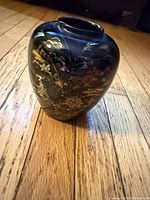 Front view of black vase showing gold floral motif