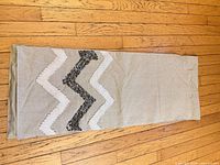 Full view of the tan table runner laid flat showing silver sequin zigzag design