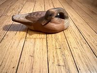 Side view of carved wooden duck on wood floor