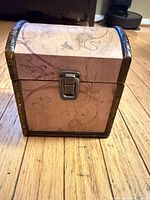 Front view of wooden trunk showing latch lock, patterned exterior, metal trim