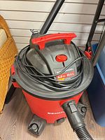 Benchmark red/black wet/dry vacuum with hose and wands visible