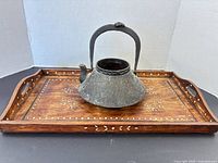 Iron kettle resting on wooden inlaid tray