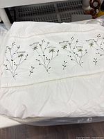Folded duvet cover showing embroidered floral band